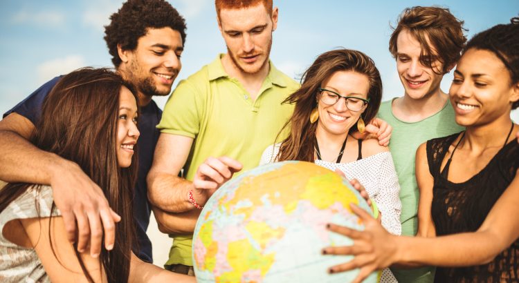 People of different ethnicity are gathered around the globe, smiling.