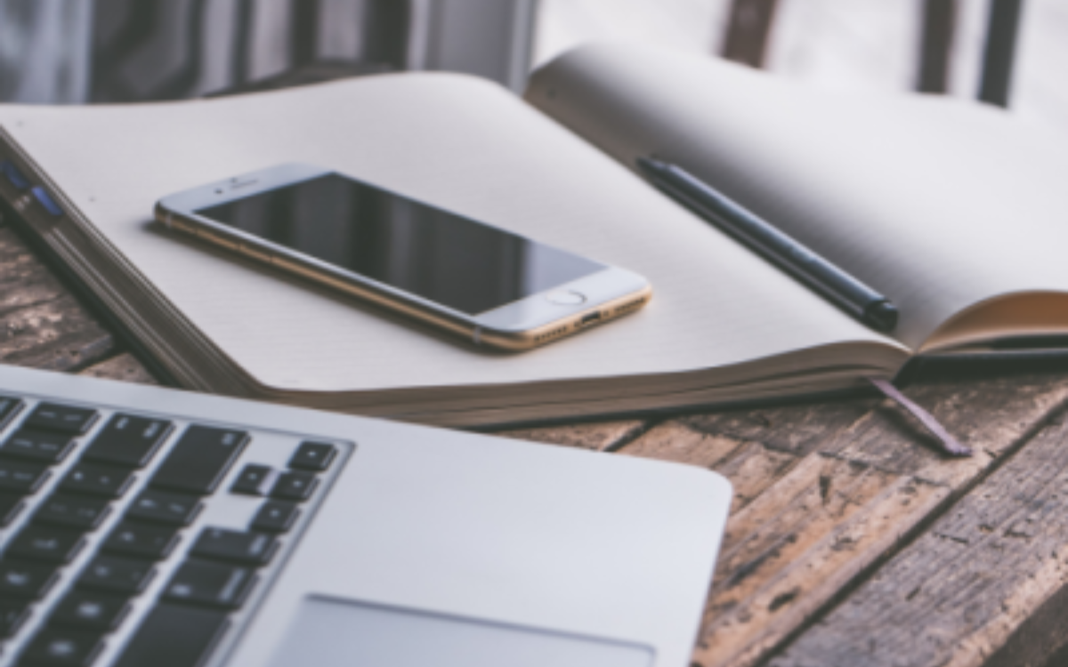 A picture of a notebook, smartphone and a laptop.