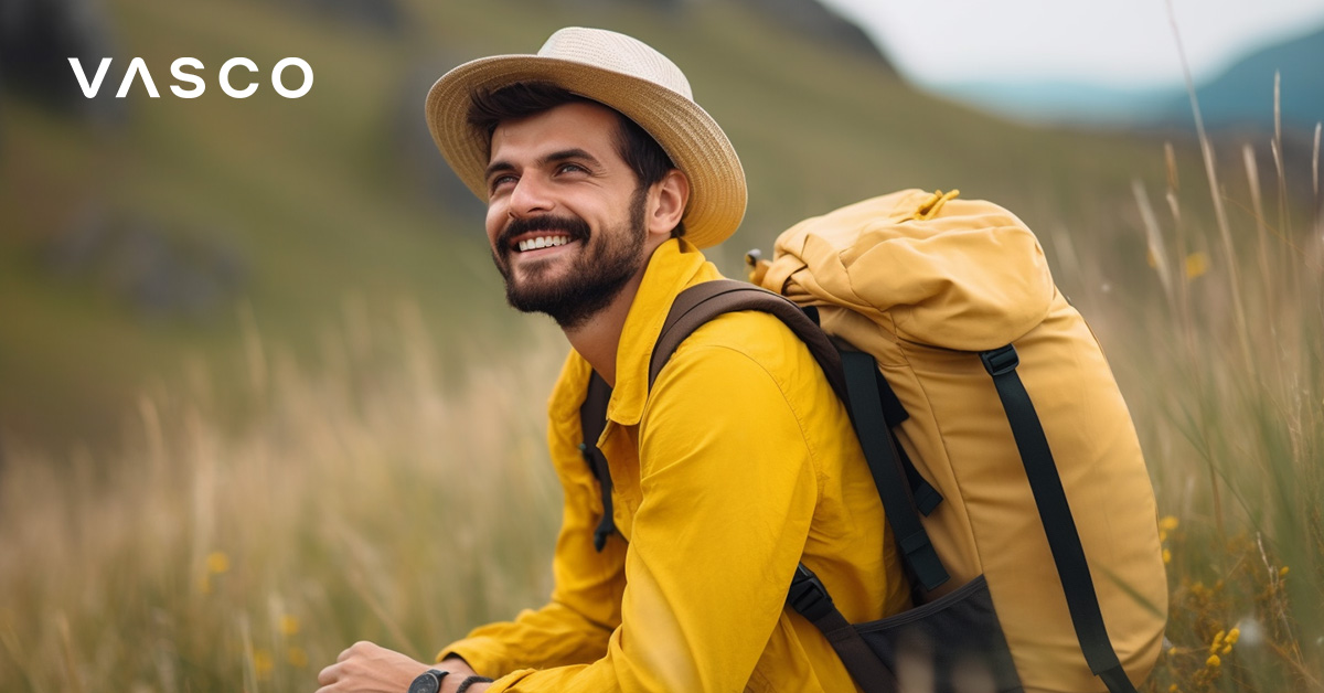 Smiling traveler on a field in yellow jacket.