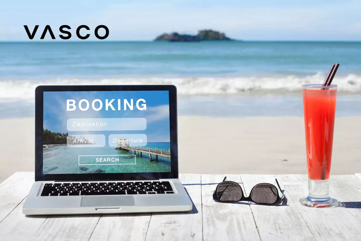 A booking platform visible on the laptop with the sea in the background.