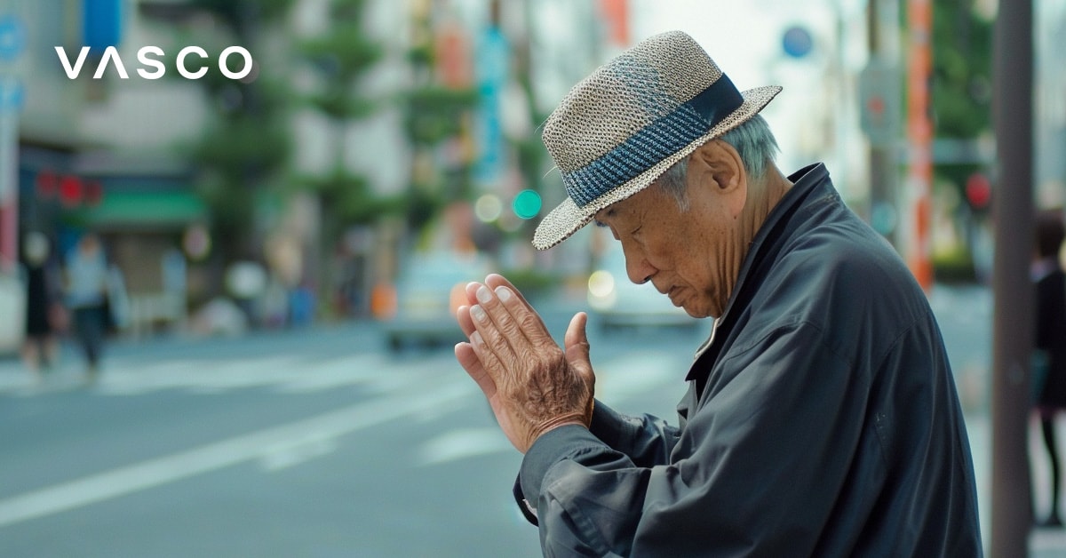 An elderly man bowing with clasped hands, representing how to say hello in Japanese.