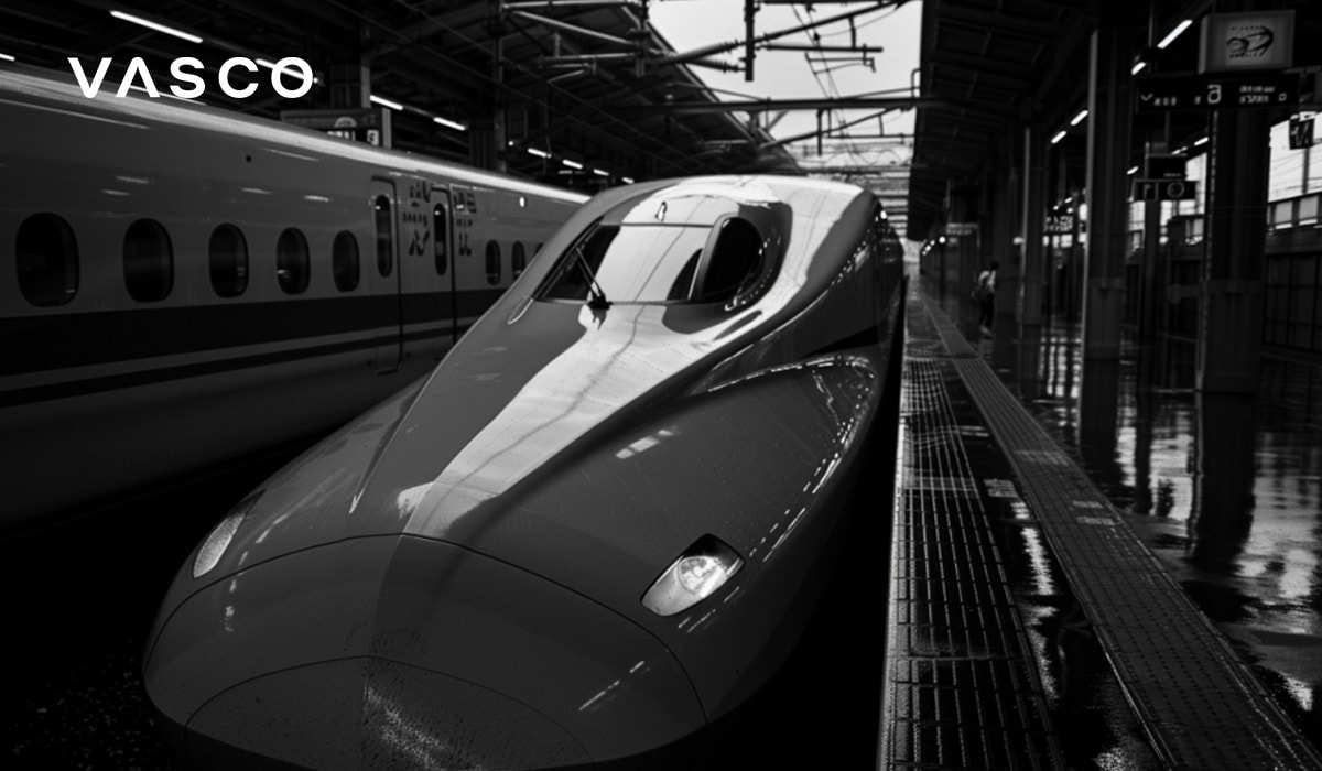 A sleek bullet train at a station platform, ready for departure, captured in black and white.