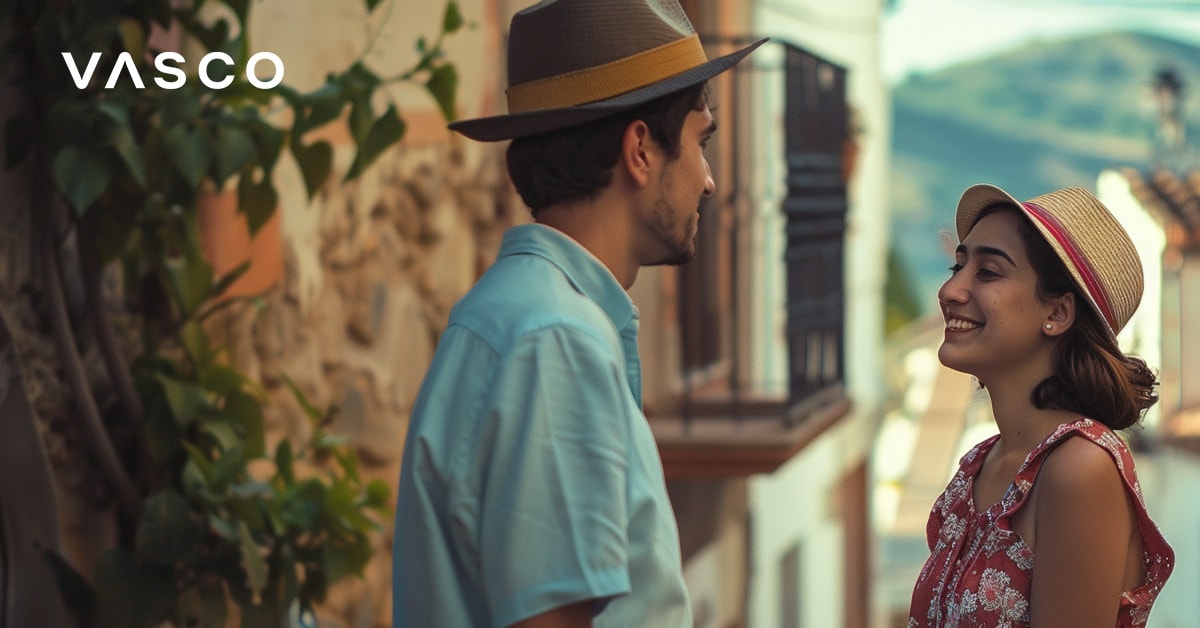 Two people conversing in a picturesque village setting, showing ways to say hello in different languages.