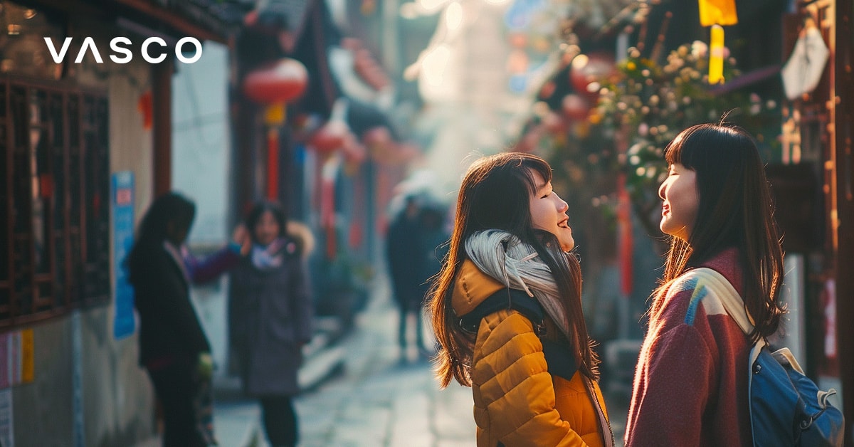 Two women talking in a busy street with lanterns, illustrating how to say hello in different languages.