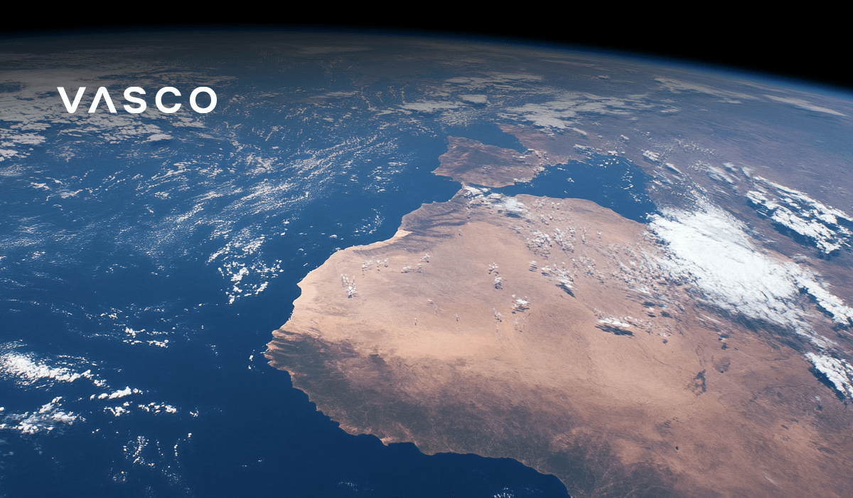 A view of the Earth from space, showing a vast desert landscape bordered by the ocean, with scattered clouds above.