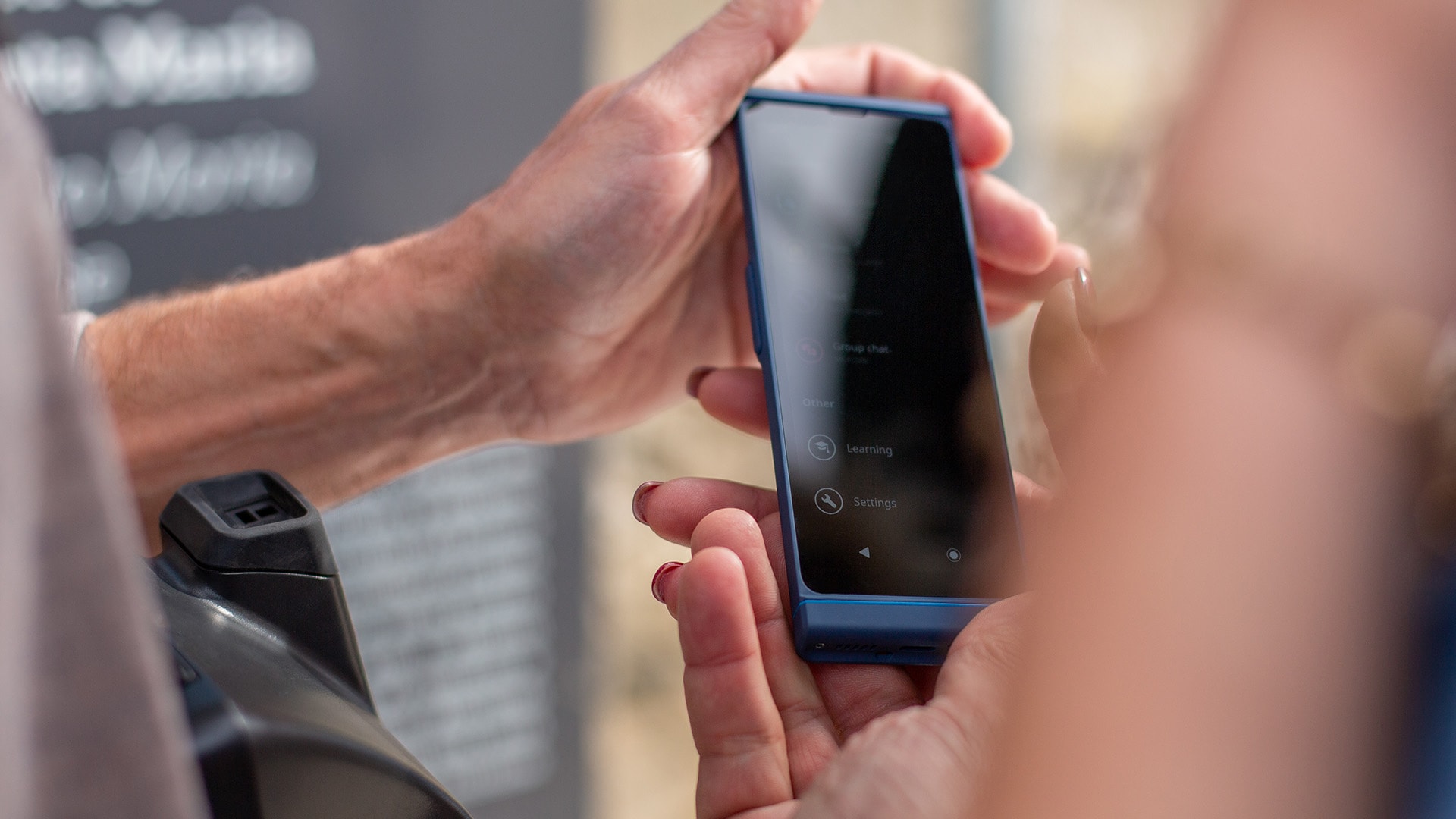 Close-up of two people holding a Vasco Translator V4 device, using it to translate text on the screen.