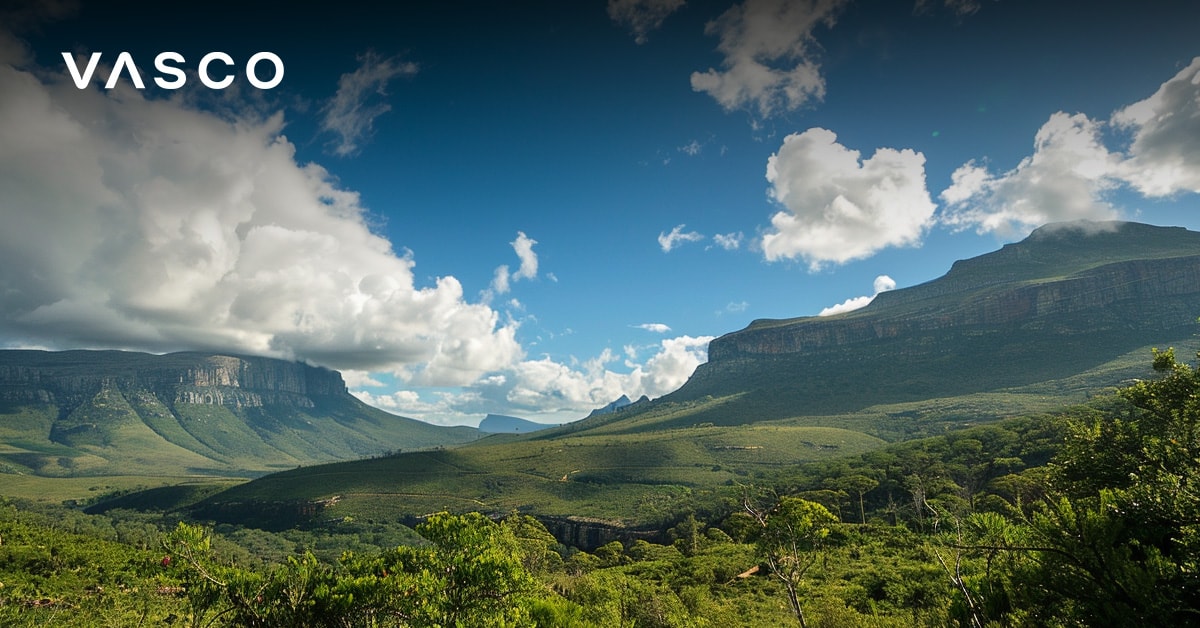 A vast green landscape with rolling hills and mountains under a blue sky with scattered clouds.