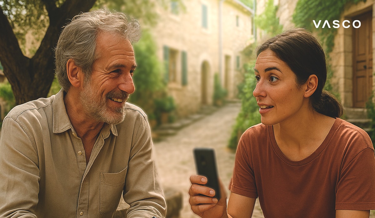 A woman holds a translation device while talking to a man in a quaint, European alleyway.