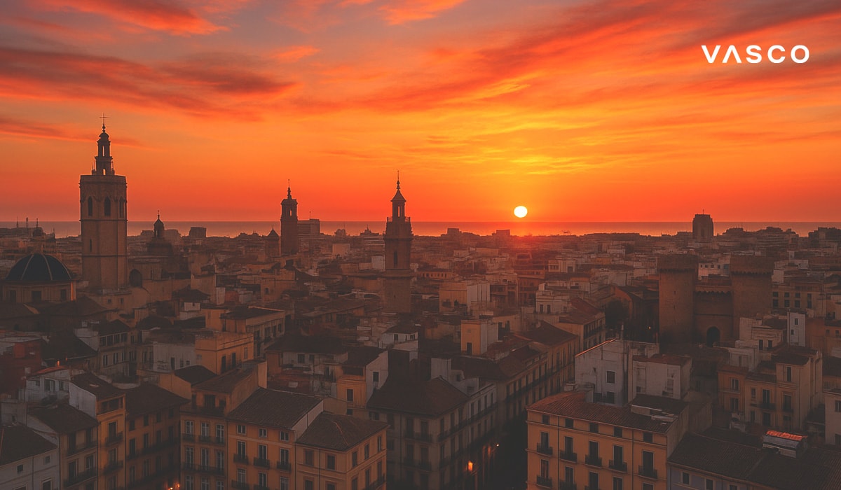 Aerial view of Valencia, Spain at sunrise with historical towers and rooftops under a dramatic orange sky.