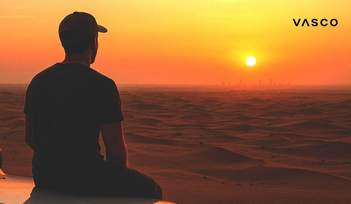 Man in a cap sitting in the desert watching the sunset with a city skyline in the background
