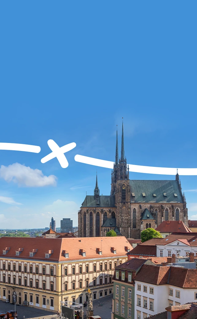 An aerial view of the historic city of Brno, Czech Republic, featuring the Cathedral of St. Peter and Paul with its prominent twin neo-Gothic spires.
