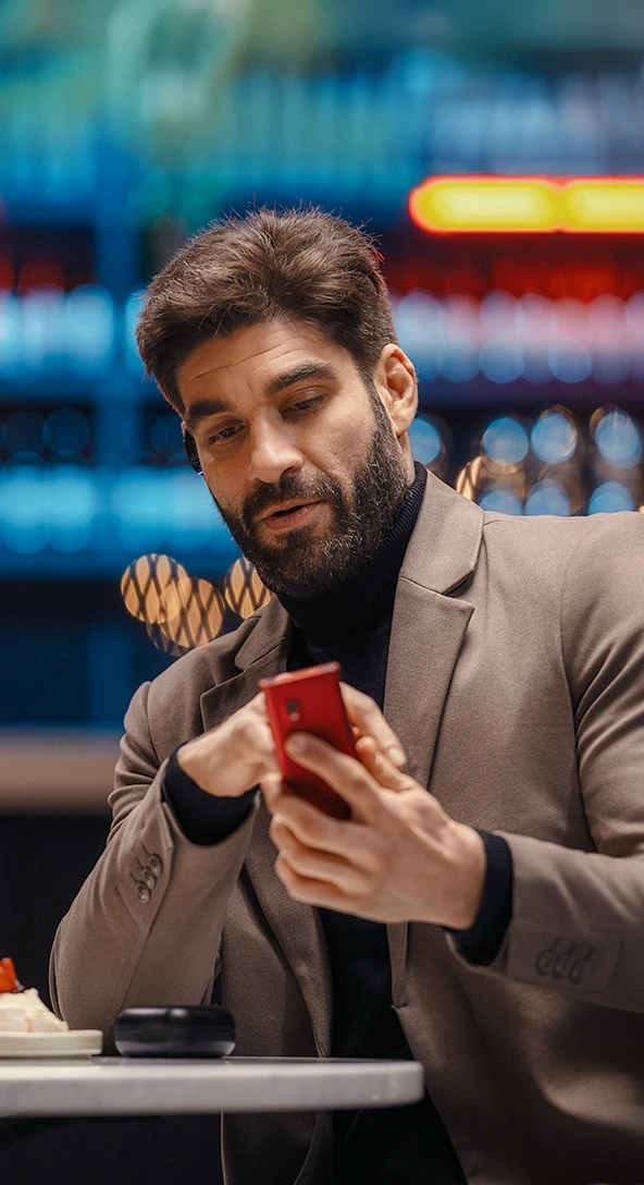 A man with a Vasco Translator E1 in his ear and a Vasco V4 in his hand, demonstrating one-button translation.