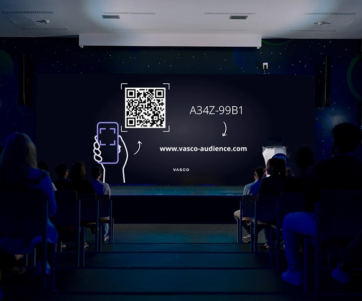 A large conference room screen displays the “Join Vasco Audience” instructions, showing guidance for participants on how to access the session.